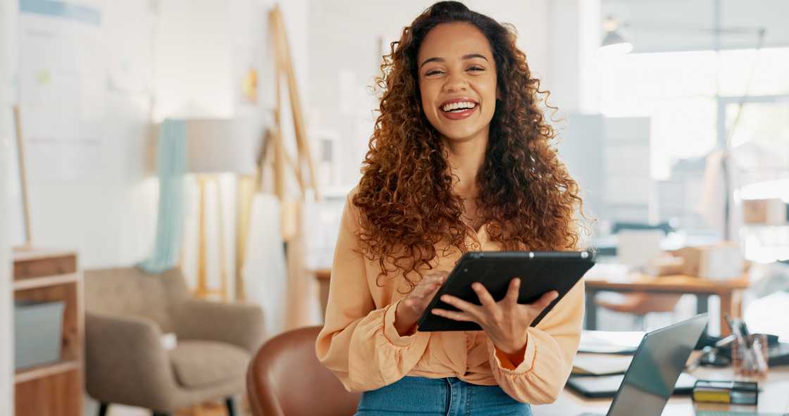 A lady smiles while holding a tablet