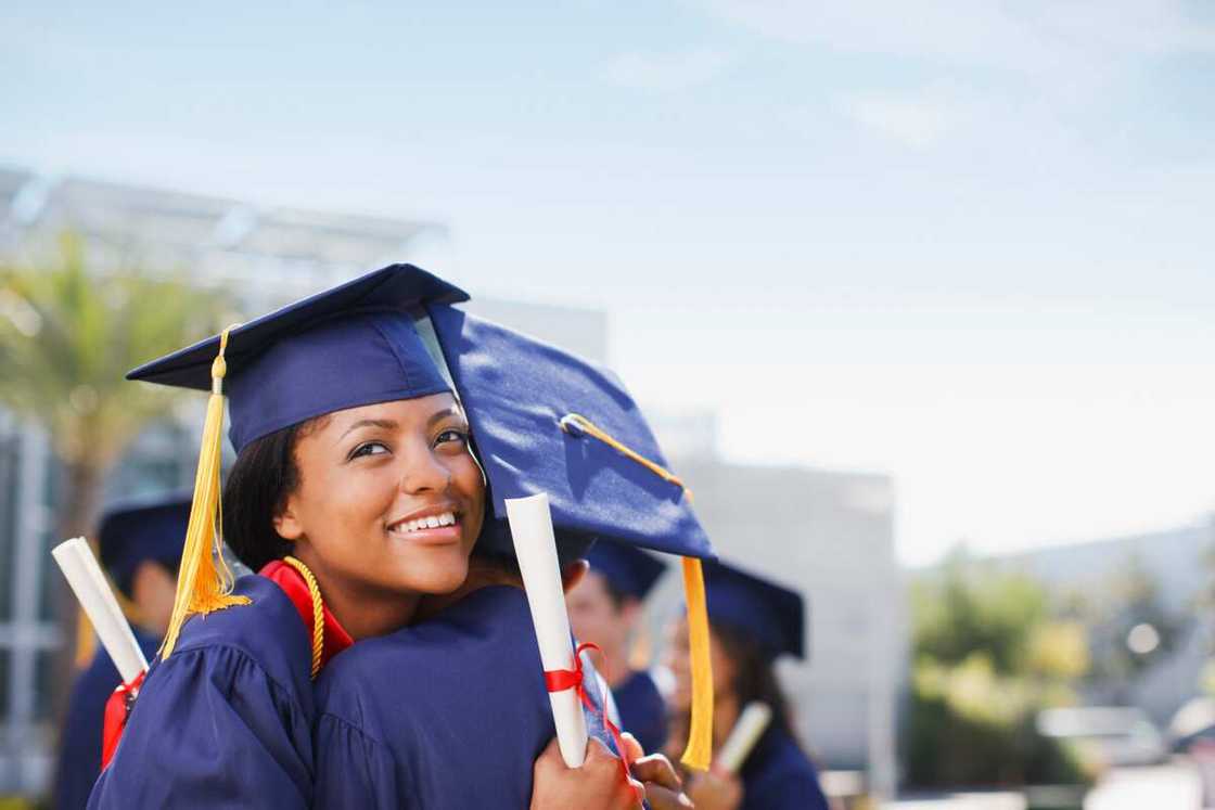 Smiling graduates hugging outdoors Smiling graduates hugging outdoors
