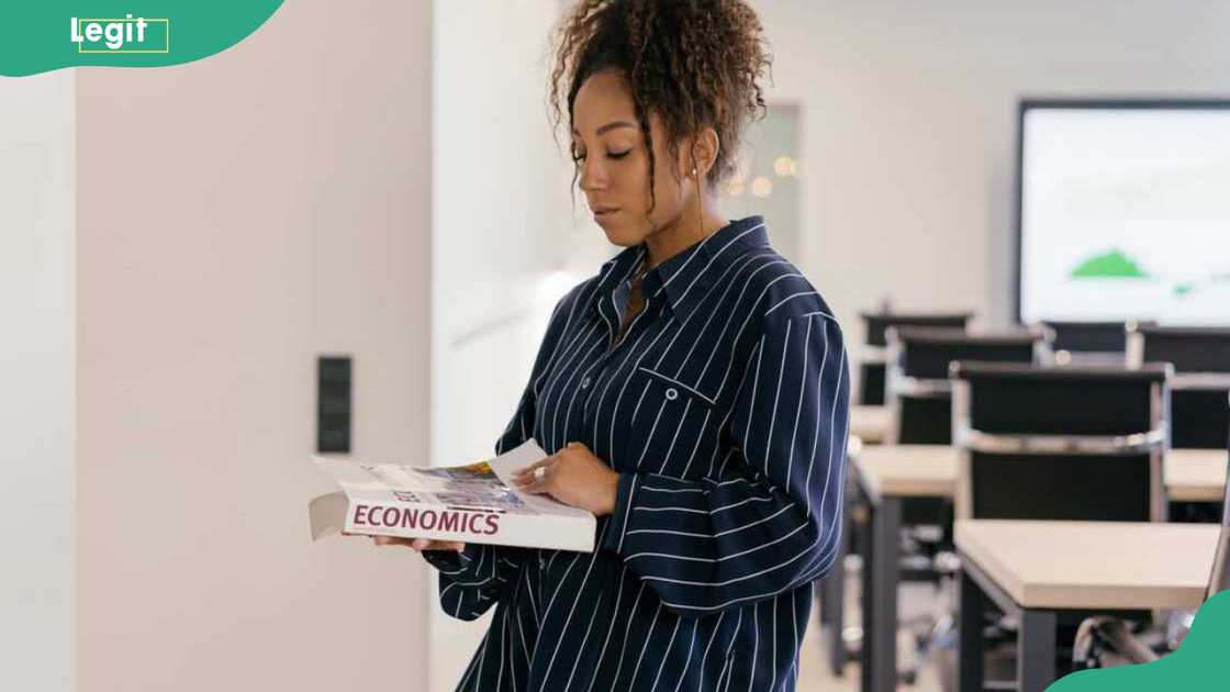 A student holding an economics course book A student holding an economics course book