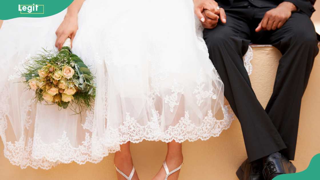 Newly wedded couple seated holding hands