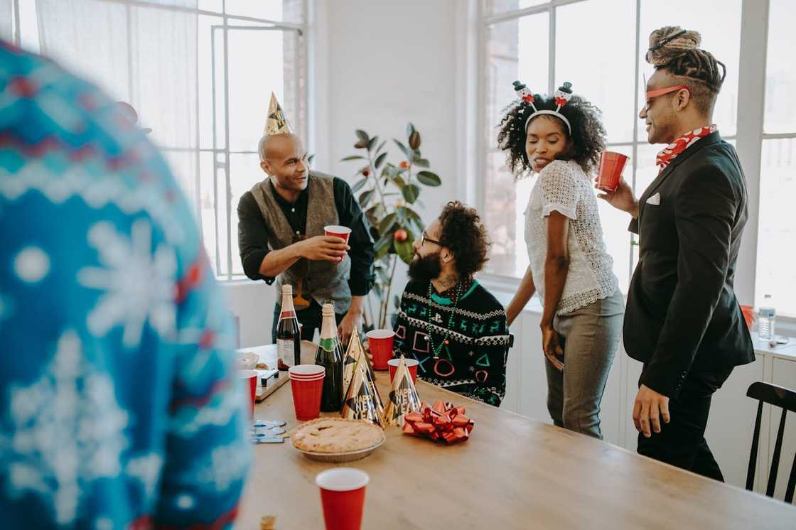 A group of people stand around a table celebrating with drinks and food.