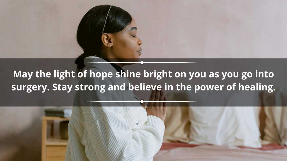 A woman in a white outfit is kneeling in prayer beside a bed