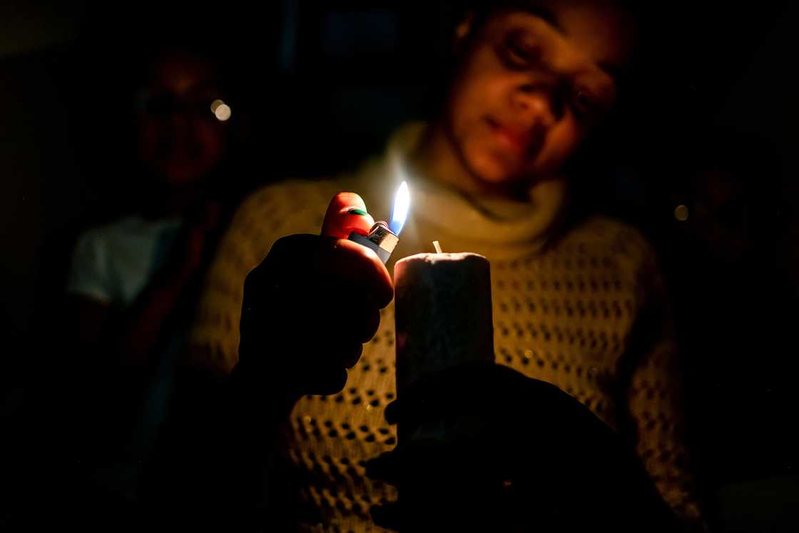 A woman lighting a candle on her balcony.