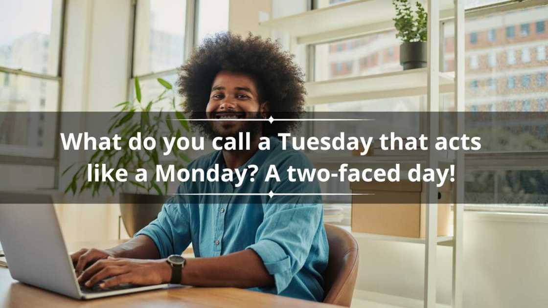 Happy, young black man wearing a blue shirt with an afro, smiling with dental braces whilst sitting at his desk using a laptop computer.