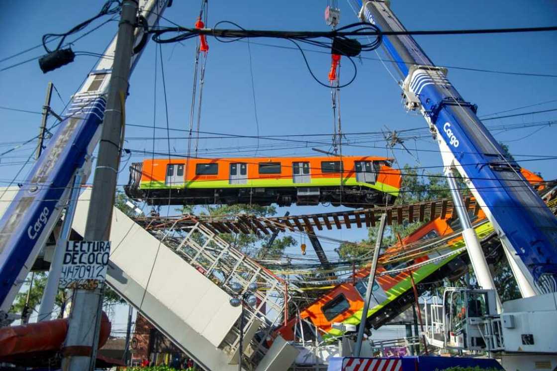 Rescue workers use cranes to remove the wreckage of a metro train that fell as an overpass collapsed in Mexico City in May 2021