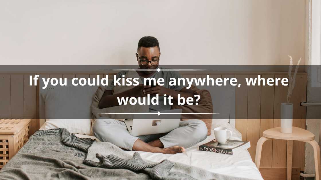A young man in glasses is texting while sitting on his bed A young man in glasses is texting while sitting on his bed