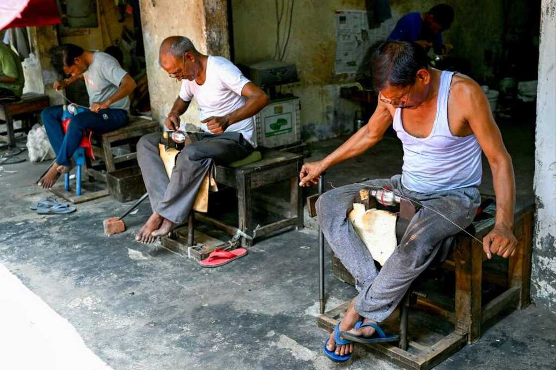 In this photograph taken on September 14, 2023, workers sculp leather cricket balls at a workshop in Meerut in India's northern state of Uttar Pradesh