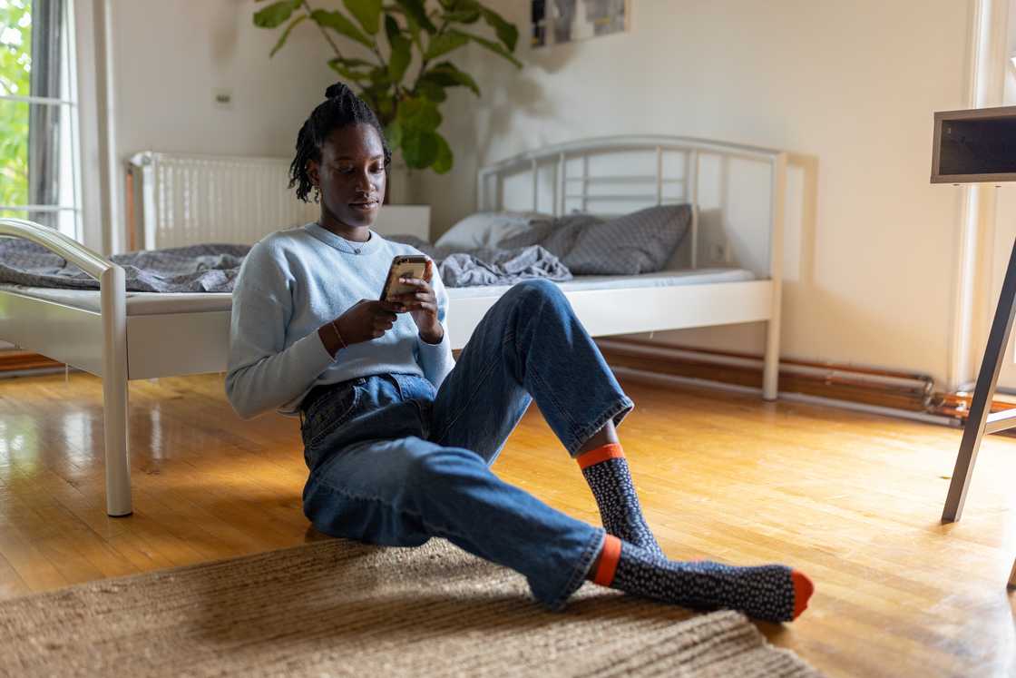 A lady is using her phone in the bedroom