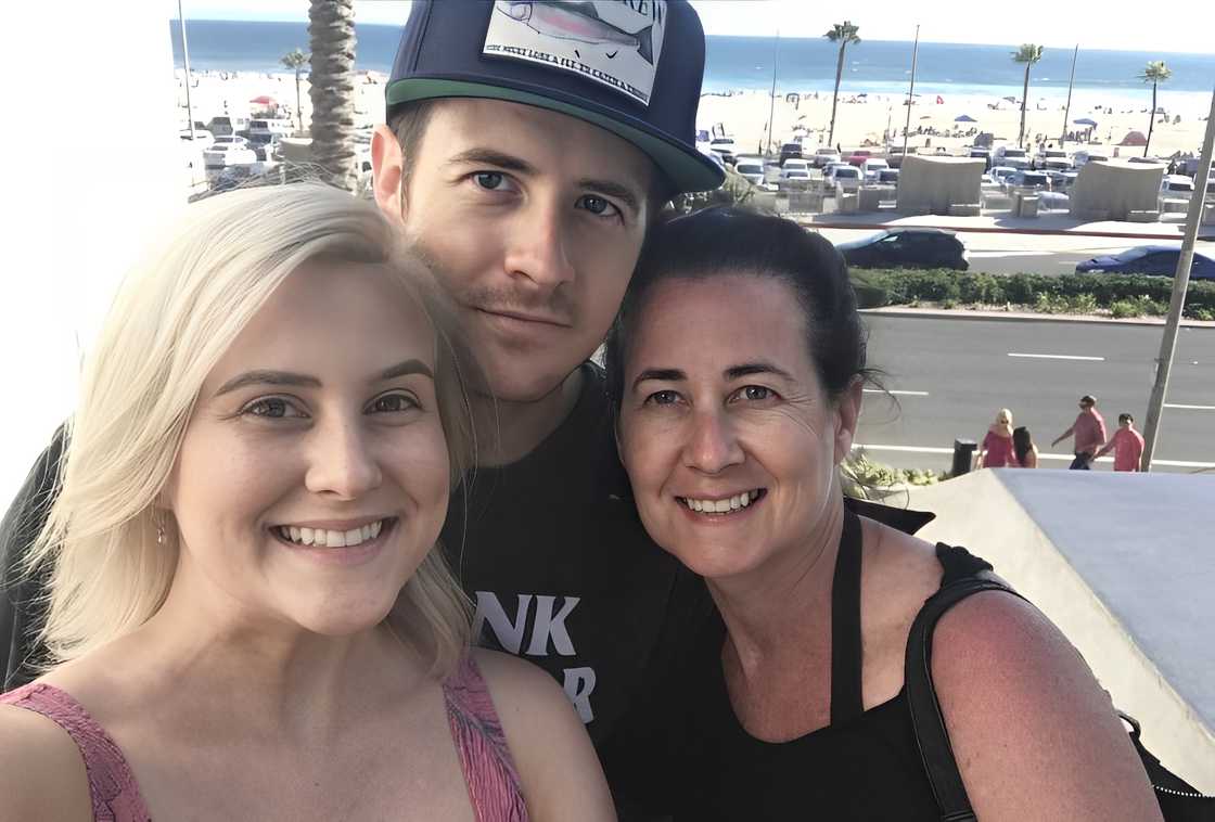 Kellsey Marie (L), Brandt Barker (C), and Randalai Barker (R) posing outside with a view of the beach in the background