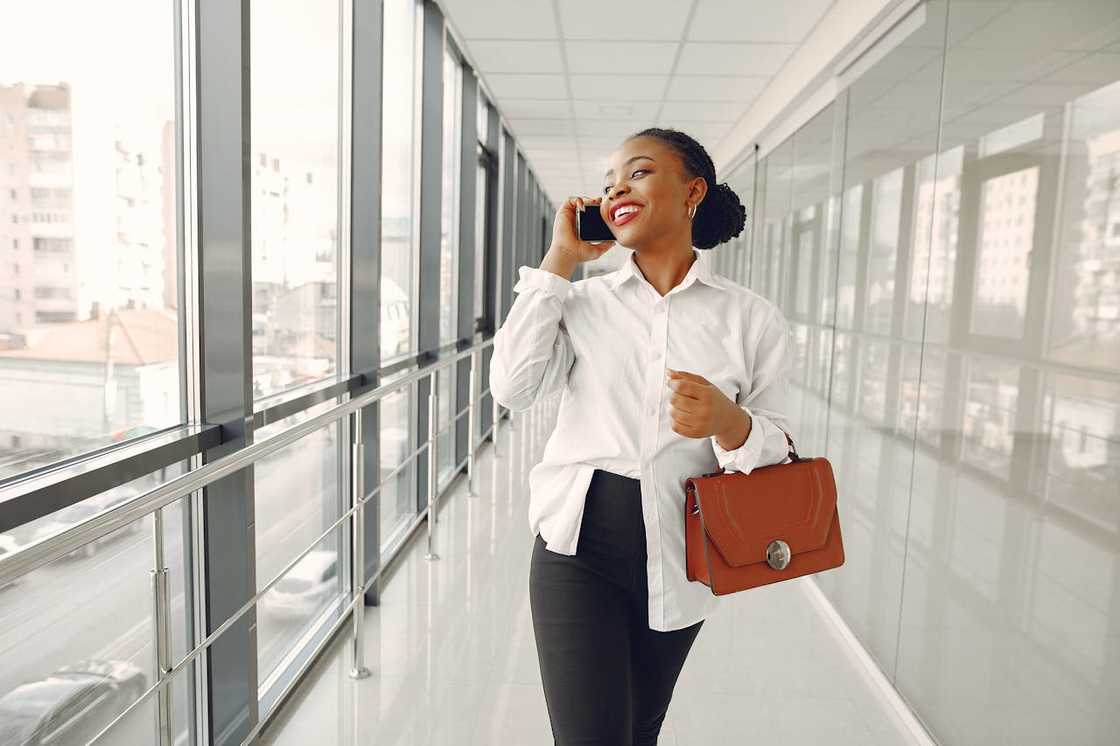 A woman walks confidently down a corridor of a modern building.