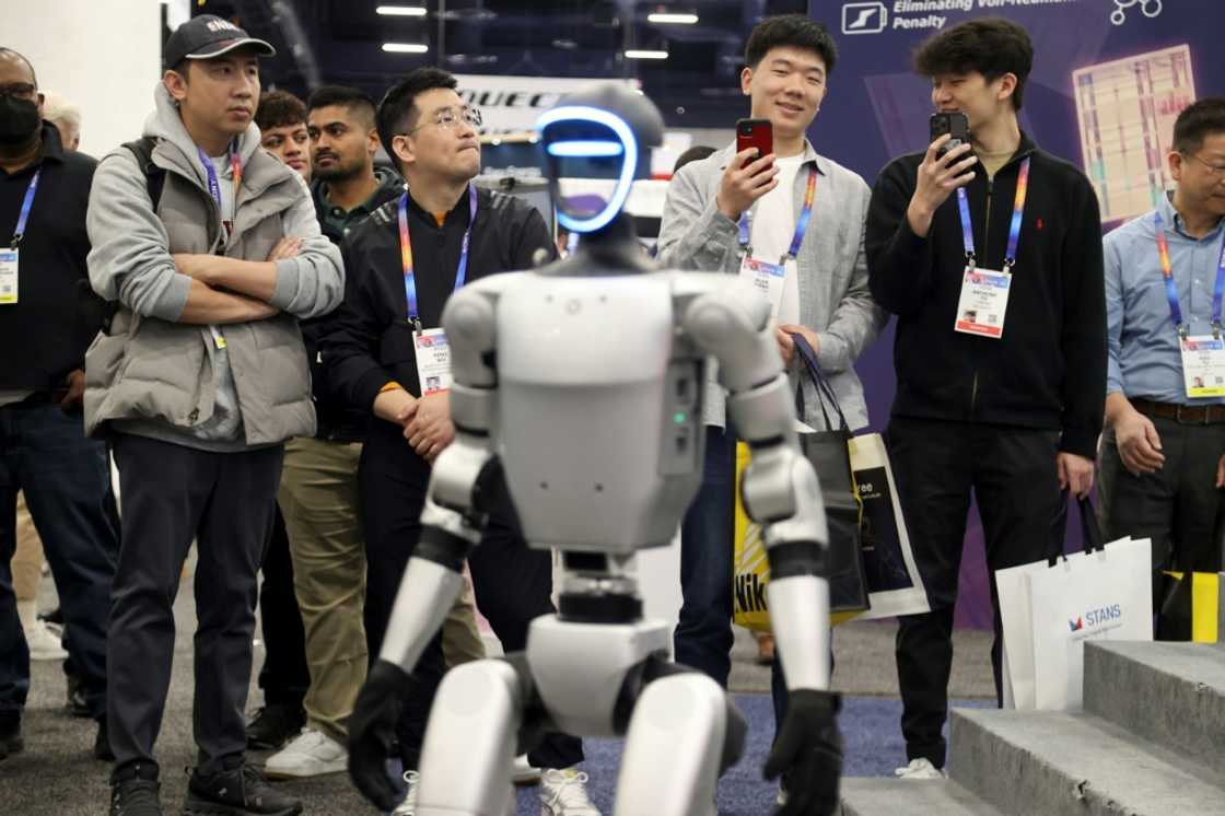 Attendees watch as a robot walks around during a demonstration at the Unitree Robotics booth during the Consumer Electronics Show (CES) in Las Vegas