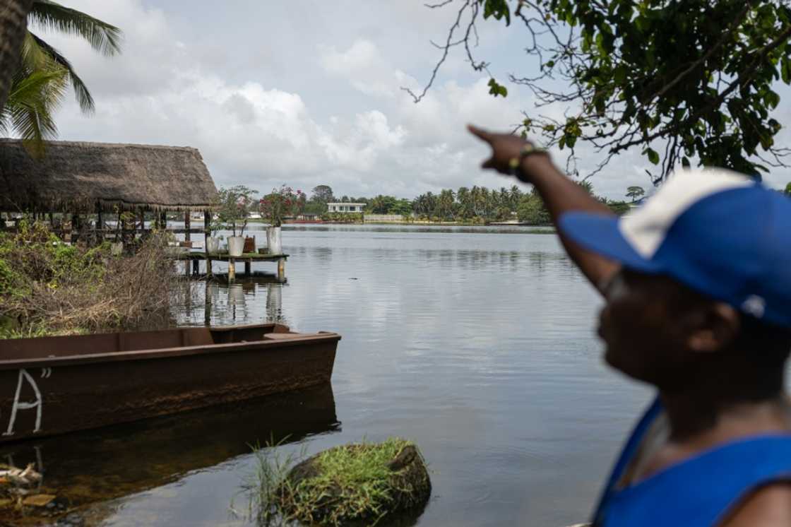 Local tour guide Pierre Ake gestures toward luxury properties overlooking the lagoon which now attracts Abidjan's wealthiest Local tour guide Pierre Ake gestures toward luxury properties overlooking the lagoon which now attracts Abidjan's wealthiest