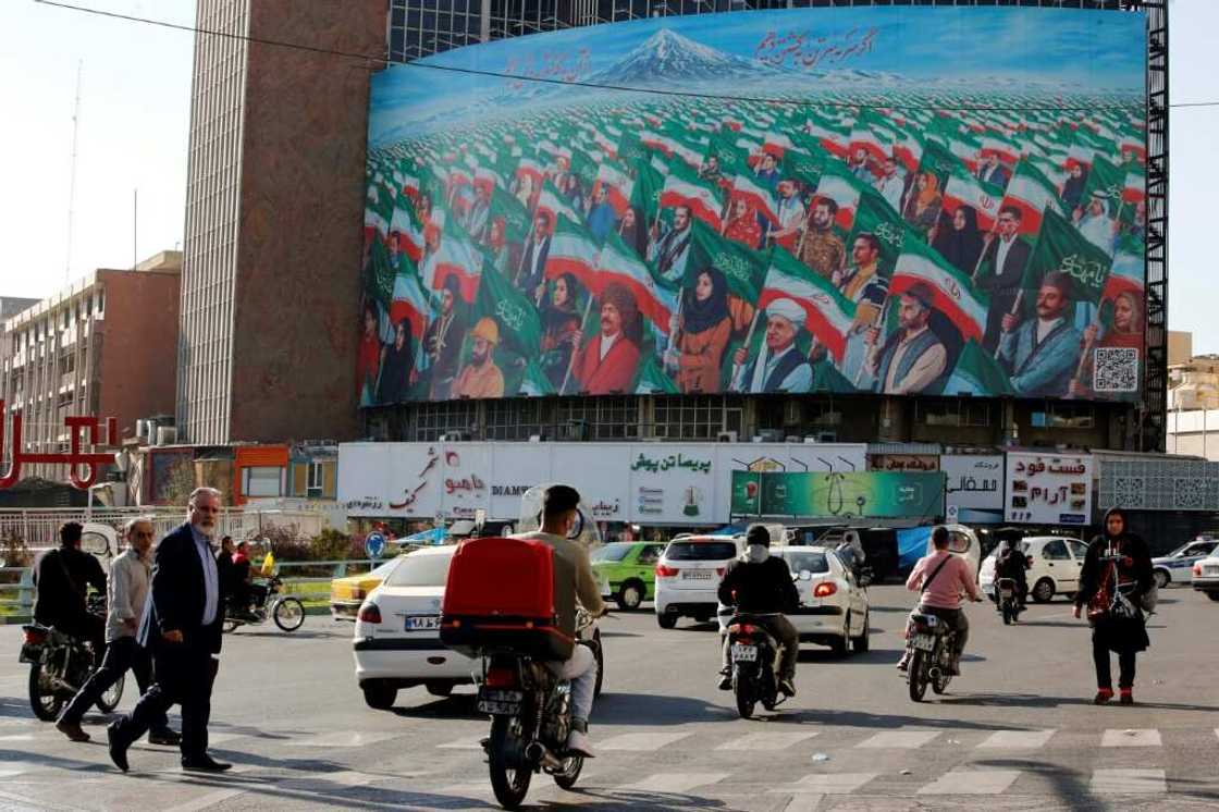 Pedestrians in Tehran's Valiasr Square near a huge billboard depicting Iranians marching with national flags Pedestrians in Tehran's Valiasr Square near a huge billboard depicting Iranians marching with national flags