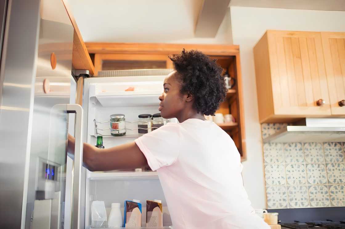 A woman is reaching into the refrigerator