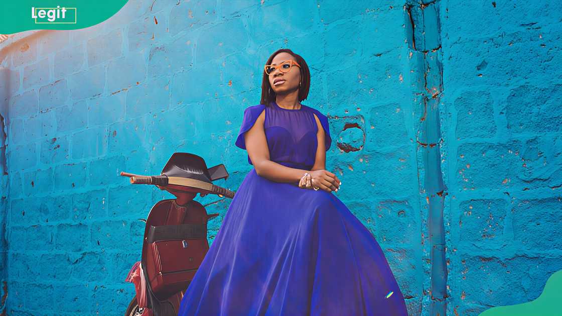 Asa Bukola in front of a scenic blue stone building