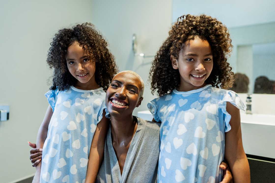 A mother and her twin daughters embracing each other A mother and her twin daughters embracing each other