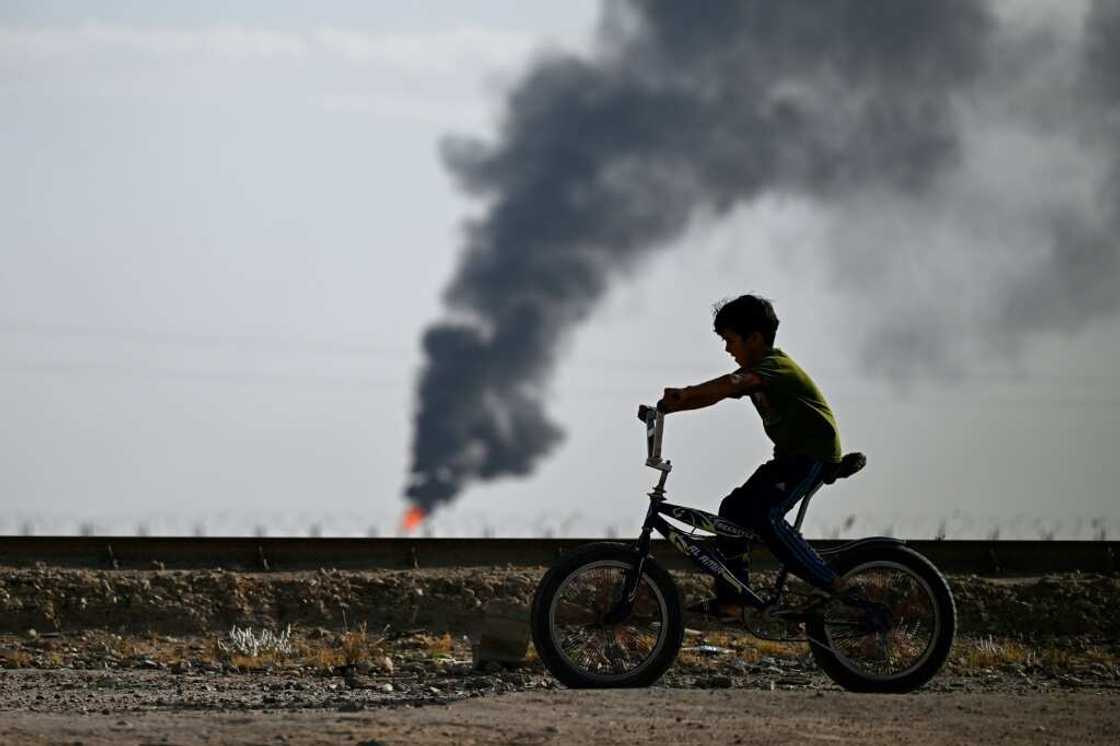 Children play football or ride their bicycles, seemingly unaware of the danger of the gas flaring around them Children play football or ride their bicycles, seemingly unaware of the danger of the gas flaring around them