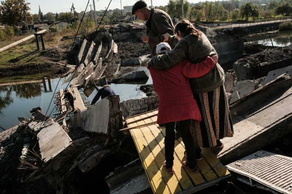 Disabled Bakhmut resident, Rimma Tsykalenko, 65, is helped by neighbours to cross a destroyed bridge on the way to her home after receiving her monthly pension payment Disabled Bakhmut resident, Rimma Tsykalenko, 65, is helped by neighbours to cross a destroyed bridge on the way to her home after receiving her monthly pension payment
