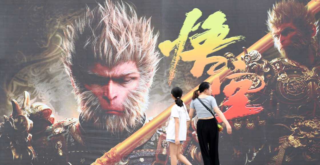People walk past a poster with Sun Wukong photo
