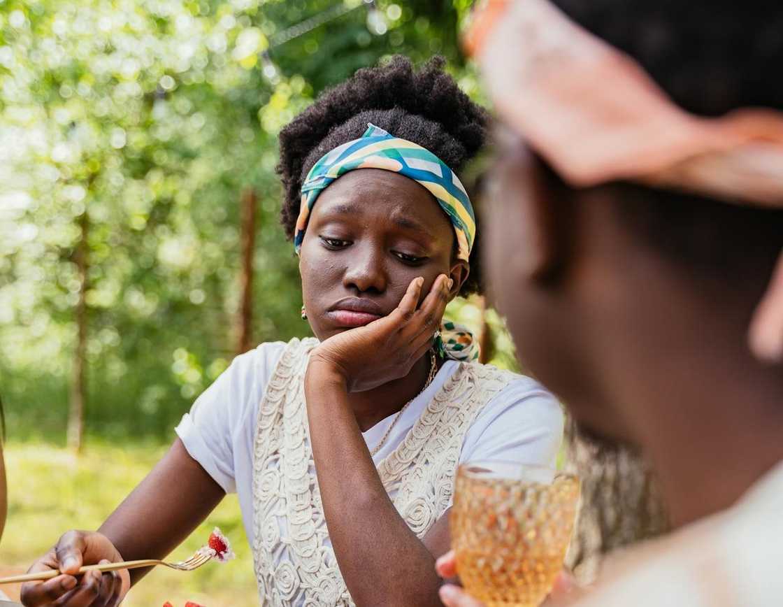 Young woman looking unhappy while sitting outdoors at a table. Young woman looking unhappy while sitting outdoors at a table.