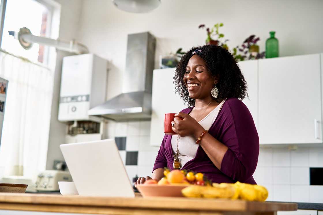 Cheerful mid adult woman using a laptop and smiling in online chat.