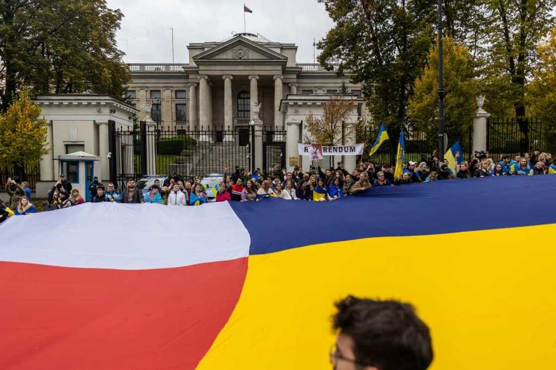 People hold a giant banner made of Poland and Ukraine's flags while attending a mock referendum on whether Warsaw should annex Russia's embassy People hold a giant banner made of Poland and Ukraine's flags while attending a mock referendum on whether Warsaw should annex Russia's embassy
