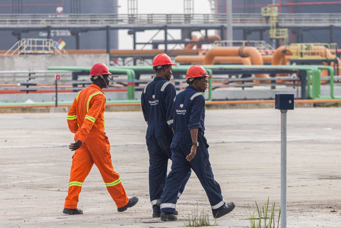 Workers dressed in orange and navy blue coveralls at the Dangote Industries Ltd. oil refinery and fertilizer plant