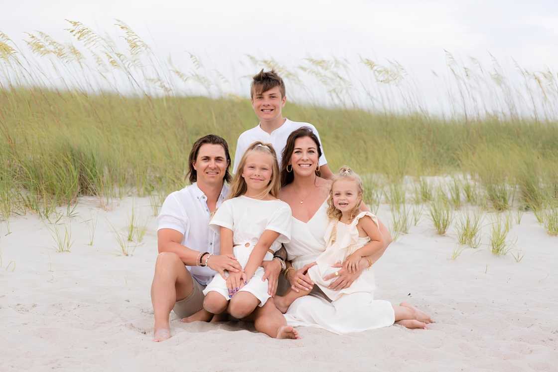 Austin Berrios, his wife Jessica Clancy and their three children posing on the sand