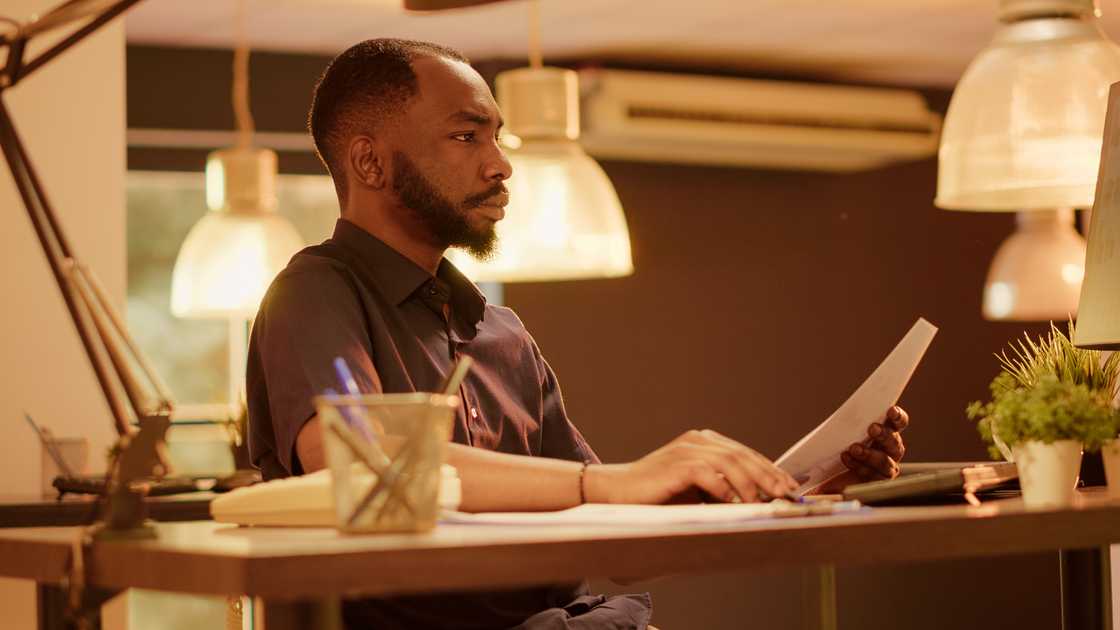 A lawyer reads a sealed letter under warm office light. A lawyer reads a sealed letter under warm office light.