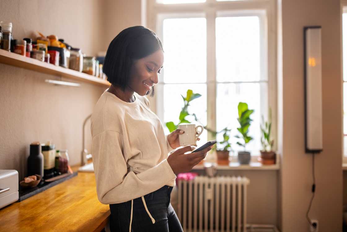 A lady smiles as she uses her phone