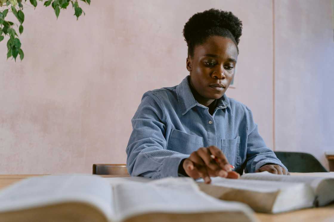 A young woman in a blue shirt is studying