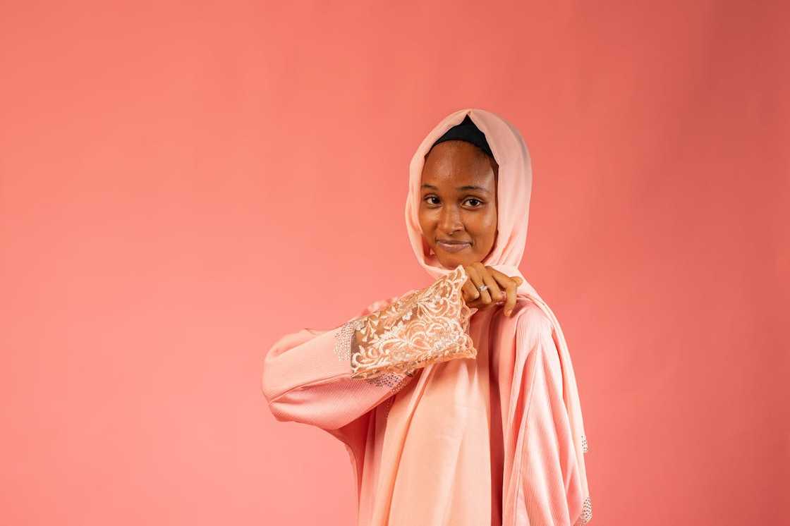 A woman wearing a pink hijab against a plain backdrop. A woman wearing a pink hijab against a plain backdrop.