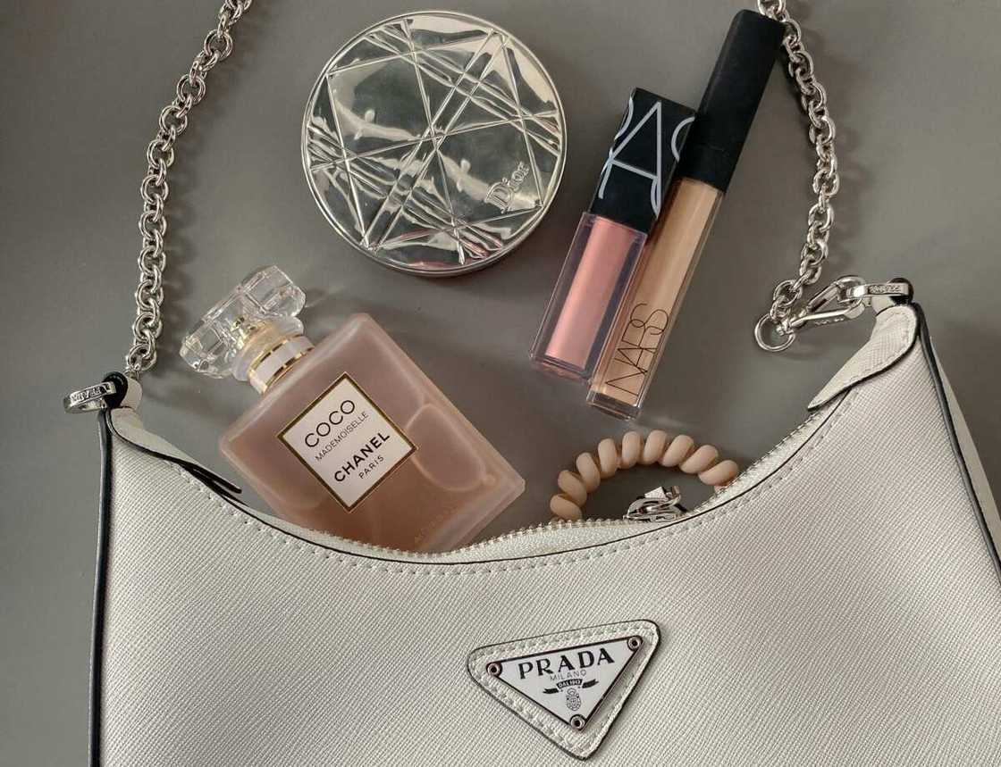 A flat lay shot of a bag with makeup and perfume A flat lay shot of a bag with makeup and perfume