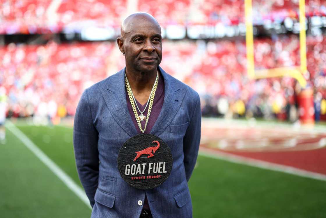 Jerry Rice of the San Francisco 49ers stands on the field wearing a “Goat Fuel” chain