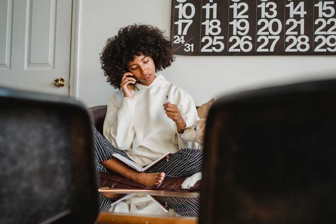 woman sitting cross-legged on a sofa, talking on the phone.