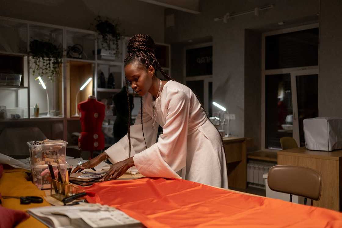 A fashion designer arranging fabric on a cutting table in a studio. A fashion designer arranging fabric on a cutting table in a studio.