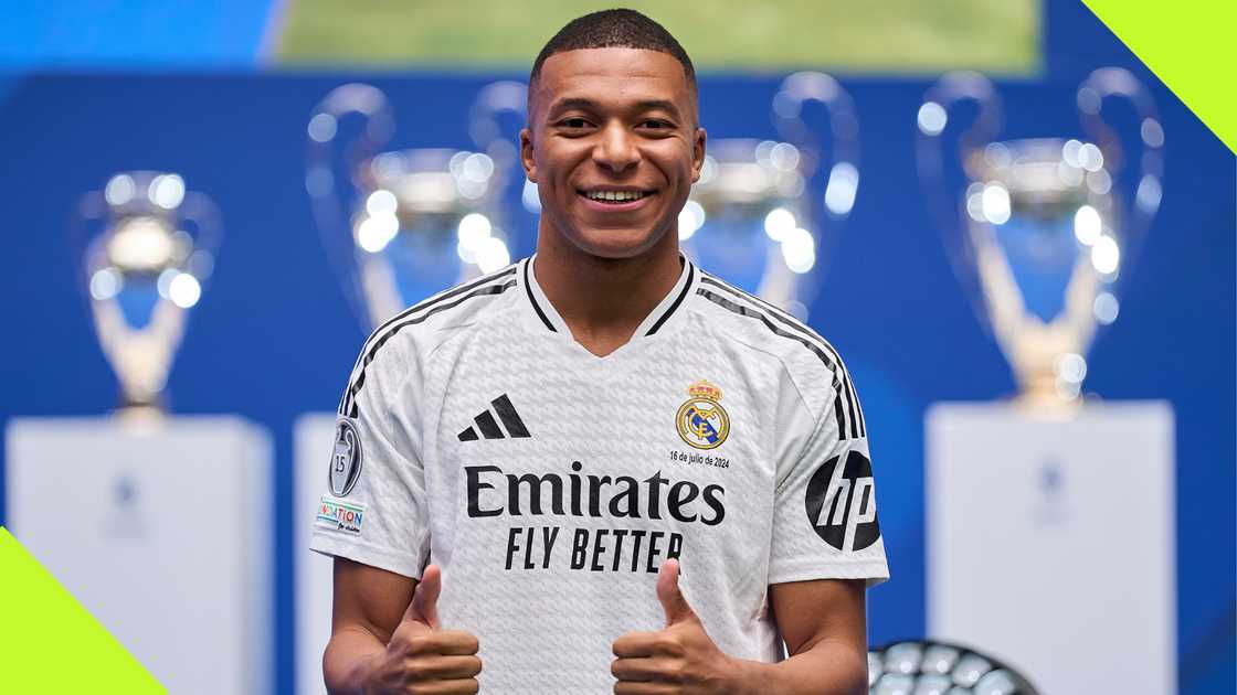 Kylian Mbappe strikes for a pose during his presentation as a Real Madrid player with the club's host of trophies in the background.