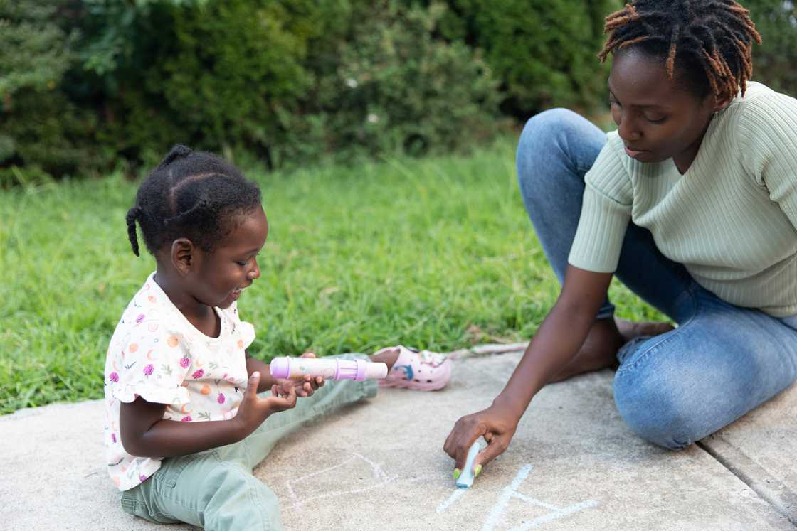 Older child helping younger girl sketching Older child helping younger girl sketching