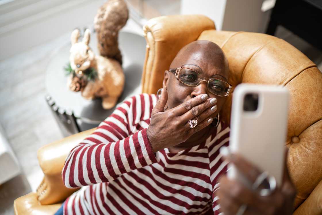 A shocked woman holding a phone indoors. A shocked woman holding a phone indoors.