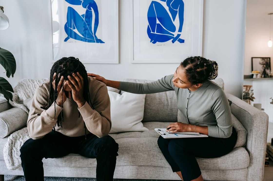 A woman comforts her boyfriend at home.