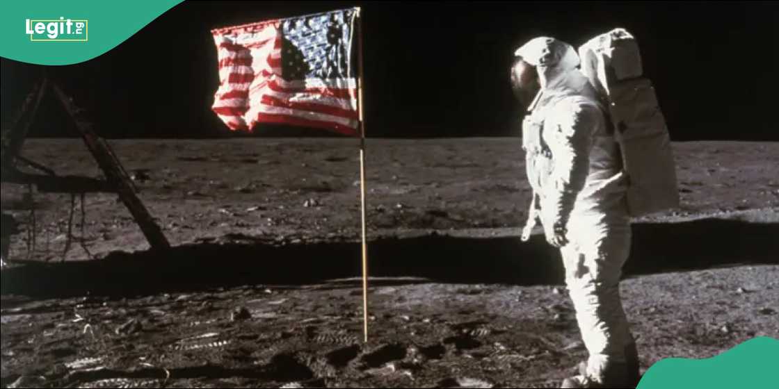 Astronaut stands beside USA flag on the moon.