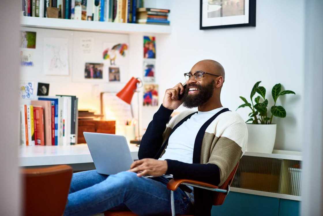 A man sitting on a chair with a laptop on a phone call A man sitting on a chair with a laptop on a phone call