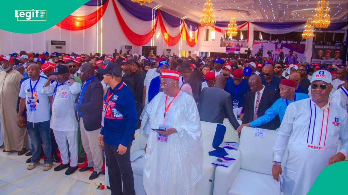 Wide shot of a packed political convention hall showing supporters and stage activity at NDC event