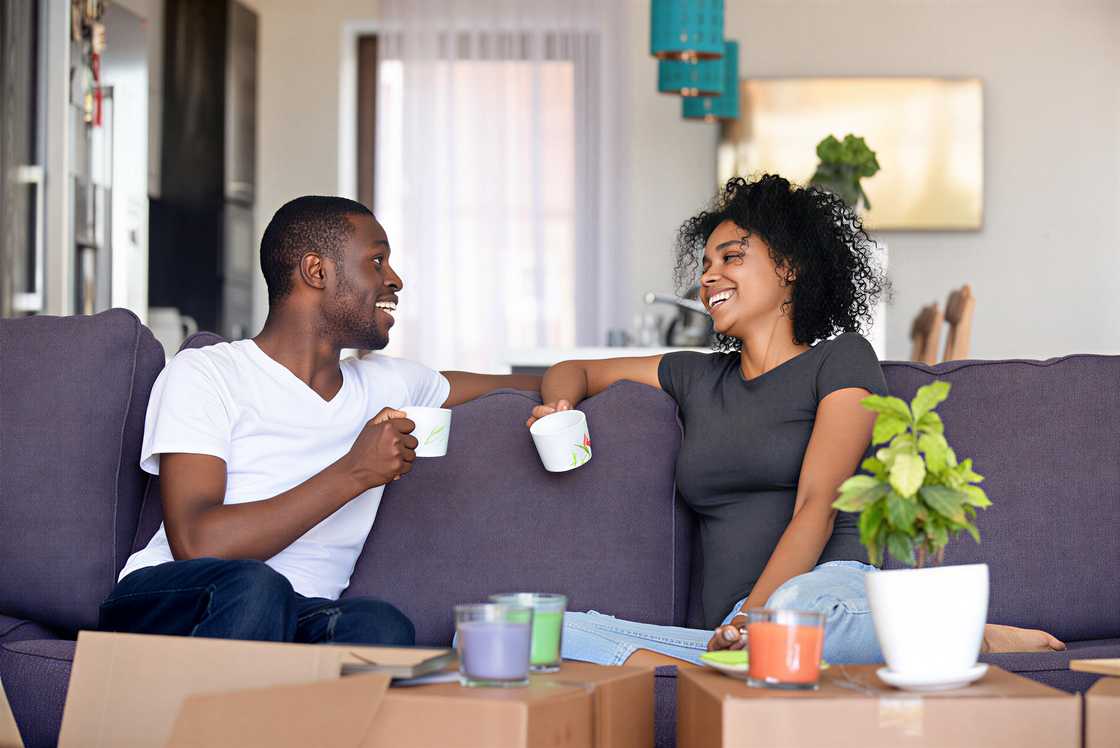 A happy Afro couple rest on a sofa