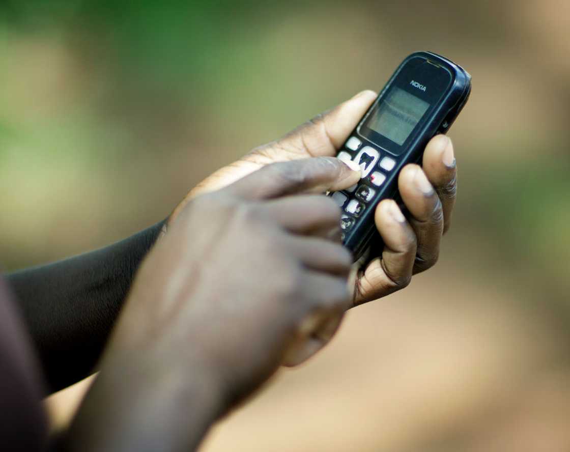 A person dialling a feature phone A person dialling a feature phone