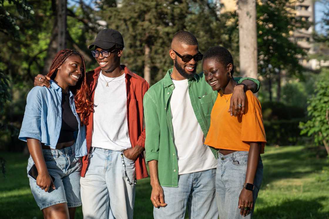 Four friends laughing on campus lawns.