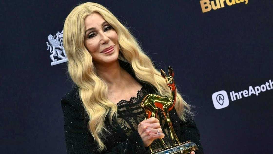 Cher posing for a photo holding an award Cher posing for a photo holding an award