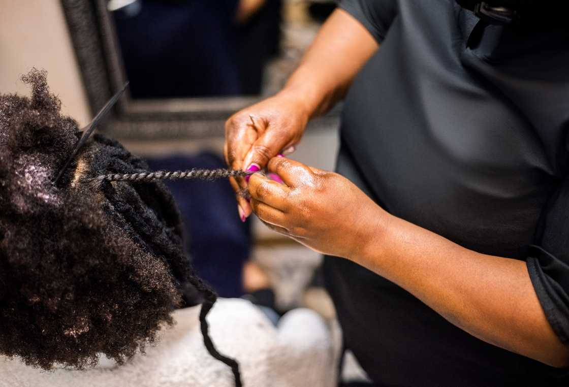 A lady plaiting a client at a hair salon