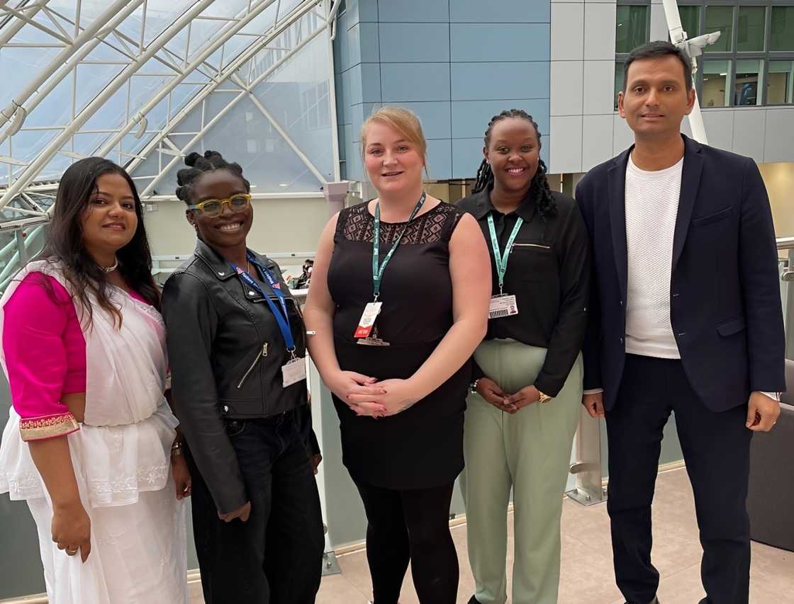 Five University of Bradford international students standing at a glass-roofed indoor space