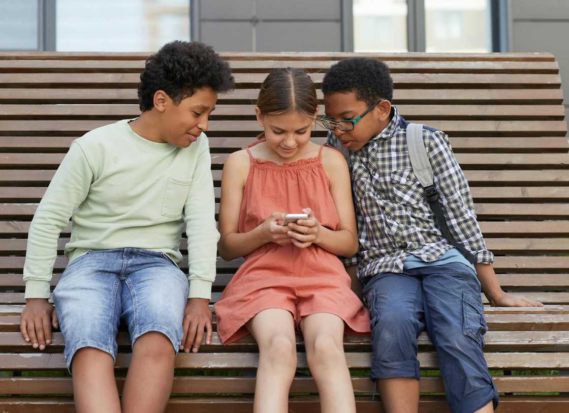 Kids looking at a smartphone together Kids looking at a smartphone together